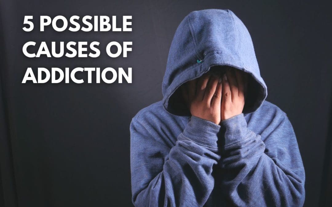 A person with their head in their hands, symbolizing the complexity of addiction's causes on a grey background.