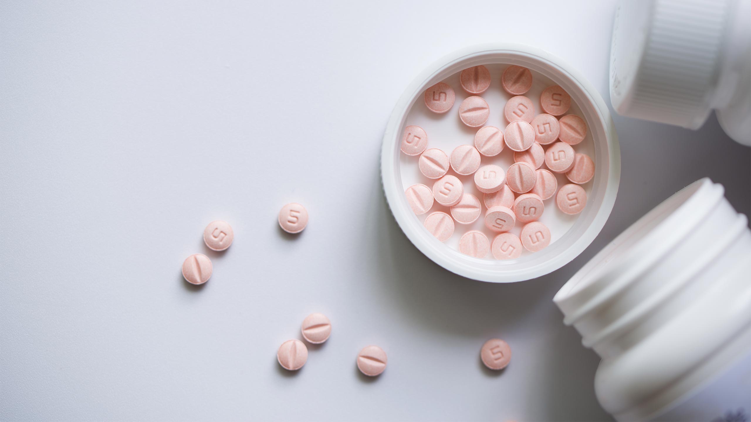 Does Trazodone Help with Anxiety? Pink pills in a pill bottle cap.
