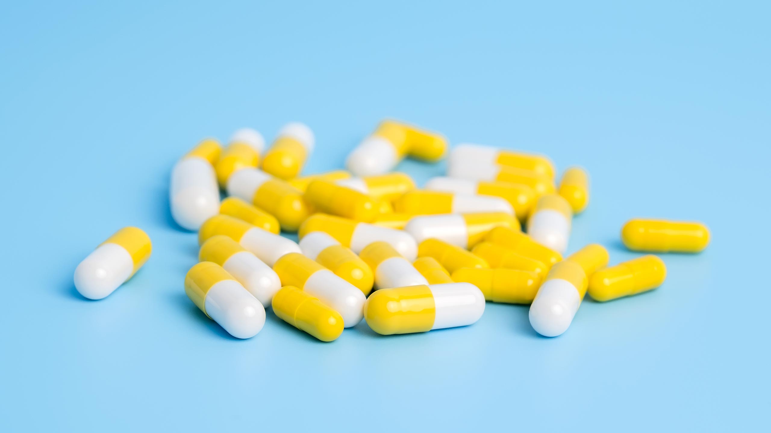 Gabapentin Withdrawal: White and yellow pill capsules on a blue surface