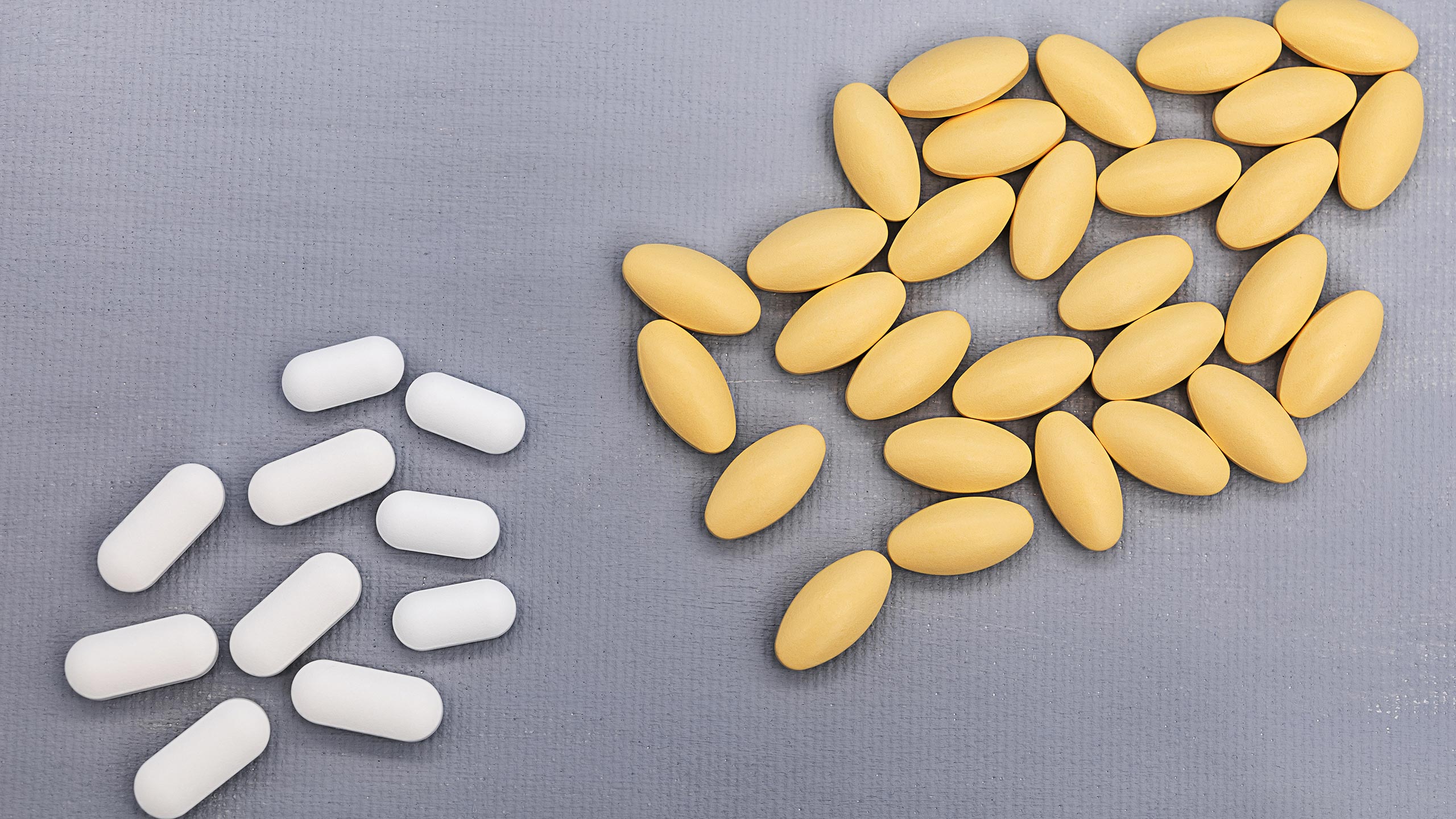 Gabapentin vs. Lyrica: White pills and yellow pills spread across a gray surface